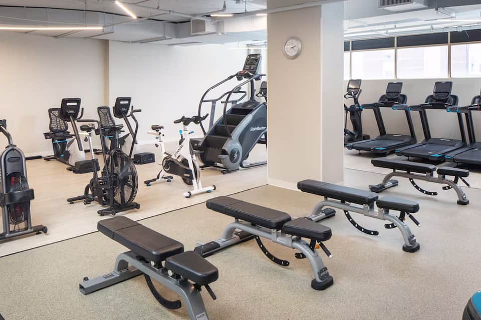 Modern fitness center with weight benches, stationary bikes, treadmills, and exercise equipment