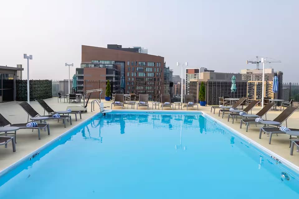 Rooftop infinity pool with blue water overlooking urban cityscape and modern buildings