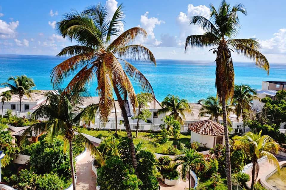 Beachfront resort with palm trees, white villas, and turquoise ocean views