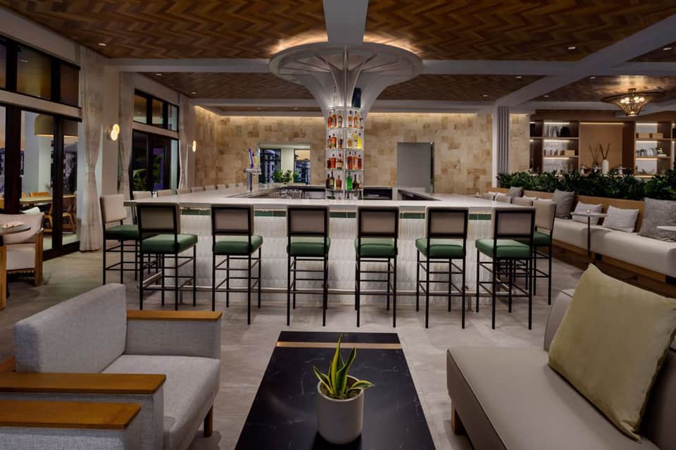 Upscale lounge bar with green leather bar stools, stone walls, wooden ceiling, and contemporary furnishings