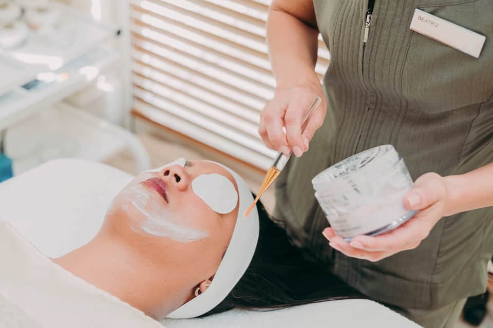 Spa professional applying facial mask treatment to client