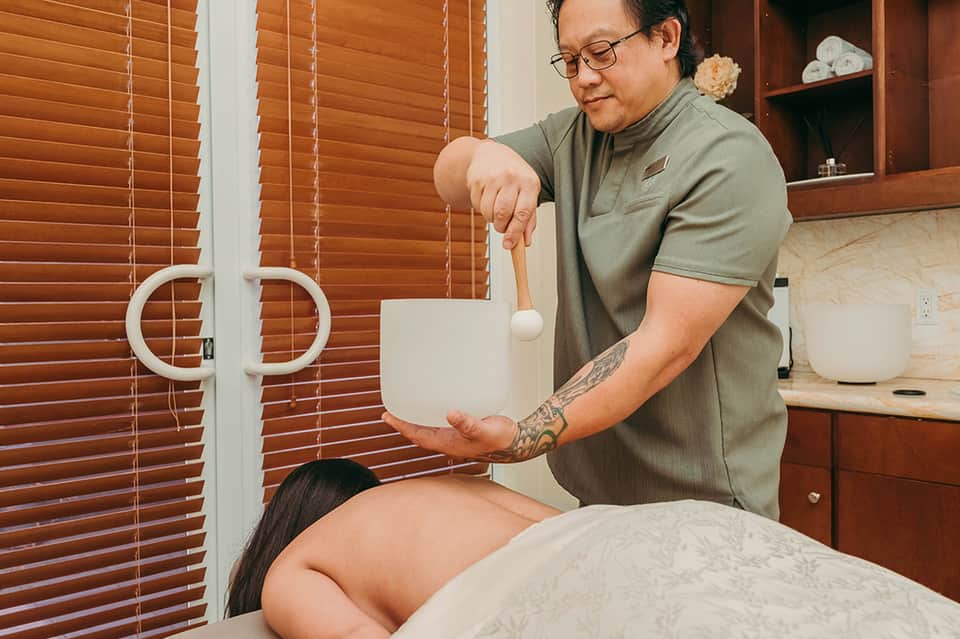 Spa therapist performing massage treatment on client using traditional healing technique