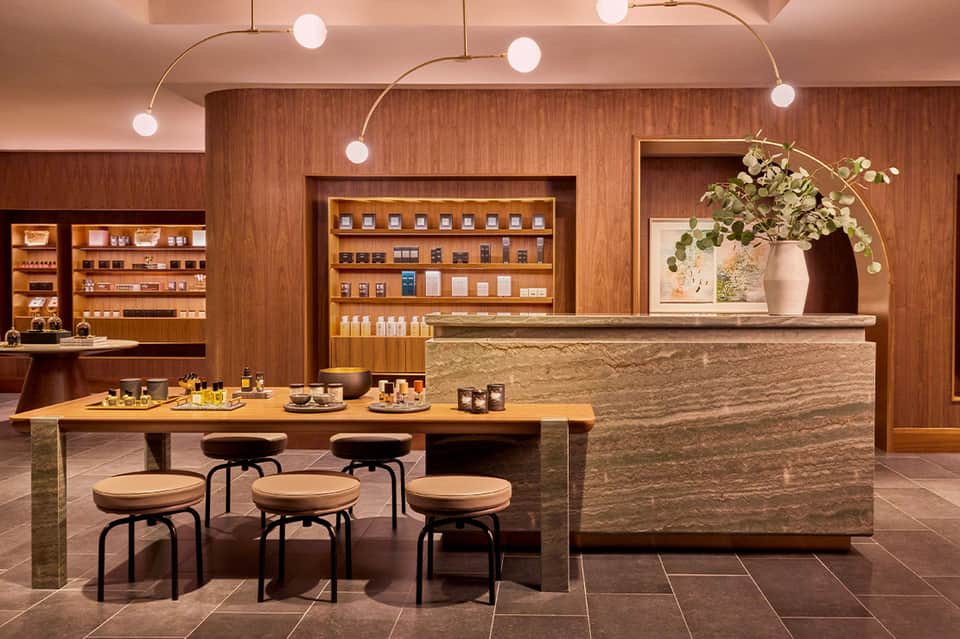 Luxury skincare boutique with wooden shelving, stone counter, organic product display, and modern pendant lighting