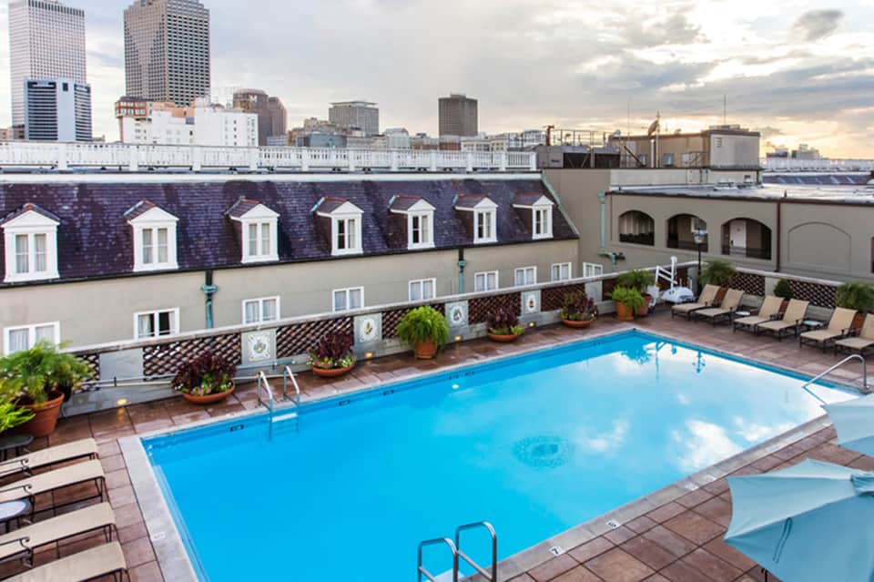 Rooftop pool with city skyline backdrop, lounge chairs, and historic architecture
