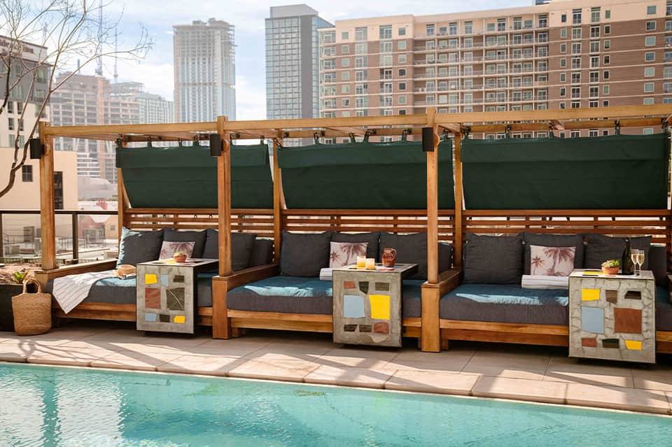 Rooftop poolside cabanas with turquoise pool and city skyline views