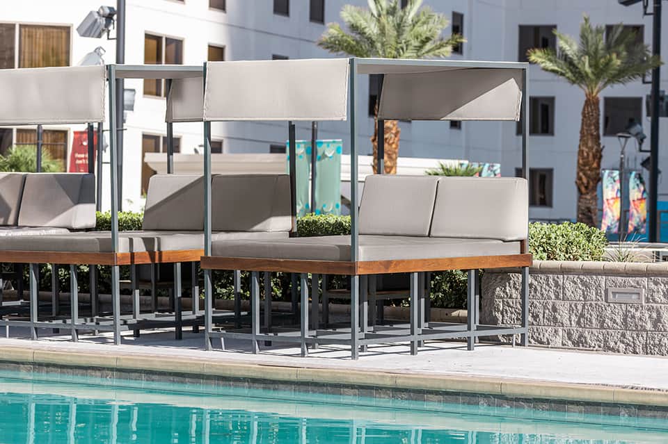 Pool lounge with modern gray cabanas and cushioned seating overlooking water