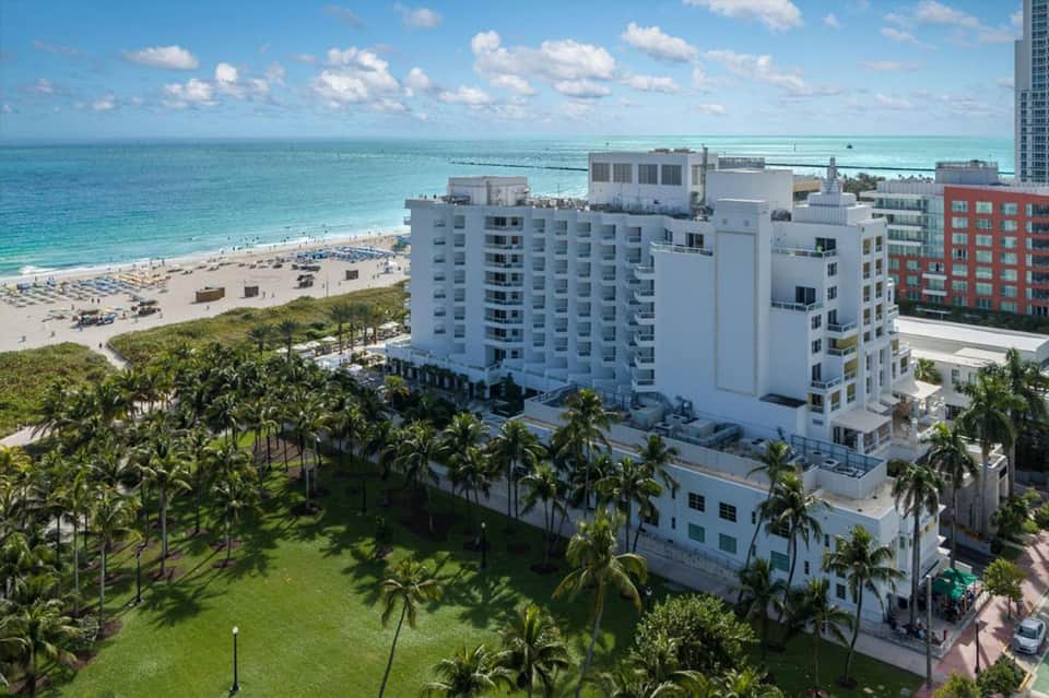 Beachfront hotel building with white facade overlooking sandy beach and turquoise ocean