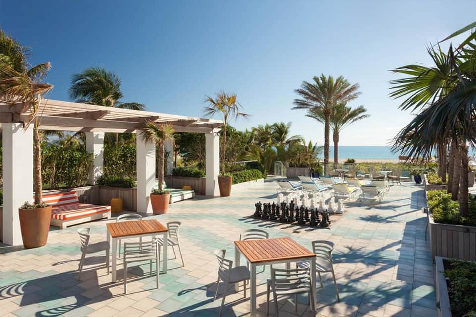 Beachfront terrace with palm trees, pergola, lounge chairs, and ocean view