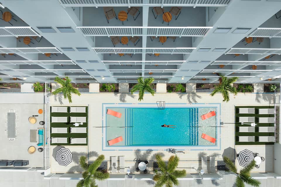 Overhead view of indoor pool with turquoise water, lounge chairs, and modern ceiling design