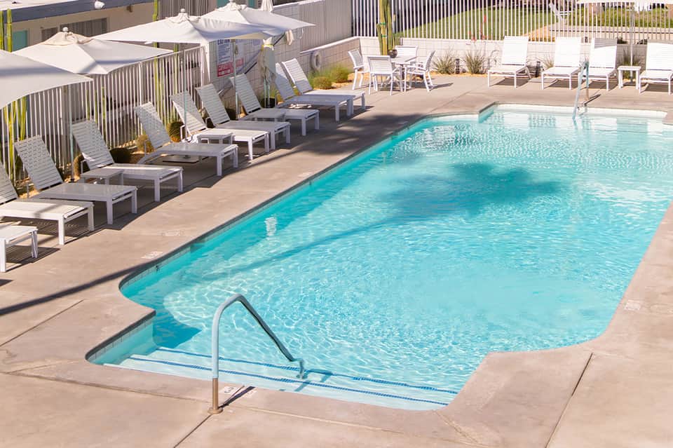 Resort pool area with loungers, white umbrellas, and turquoise water