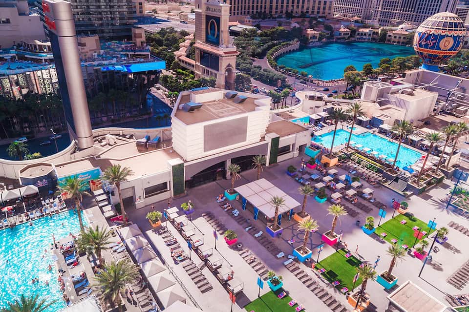 Aerial view of luxury resort with turquoise pools, palm trees, and high-rise hotels in Las Vegas