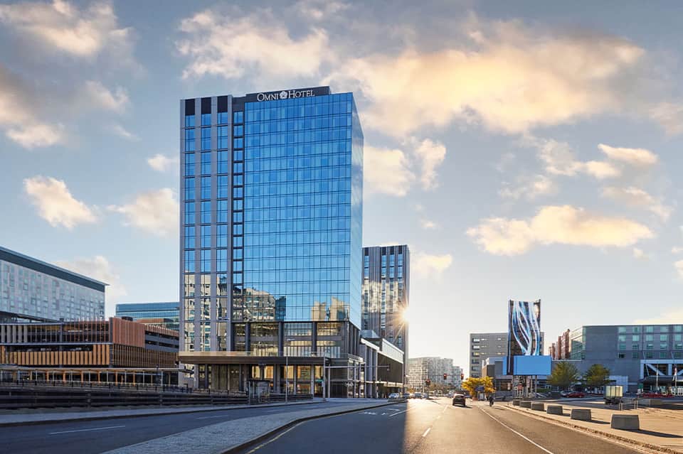 Modern Omni Hotel with glass facade in contemporary waterfront district under cloudy sky
