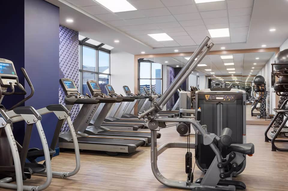 Modern fitness center with treadmills, exercise bikes, and strength training equipment with large windows