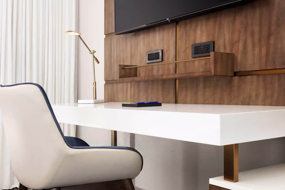 Modern minimalist office workspace with white desk, wood-paneled wall, and flat-screen TV