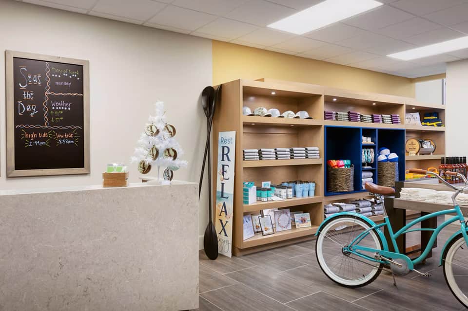 Modern spa reception area with wooden shelving, retail products, and a turquoise bicycle