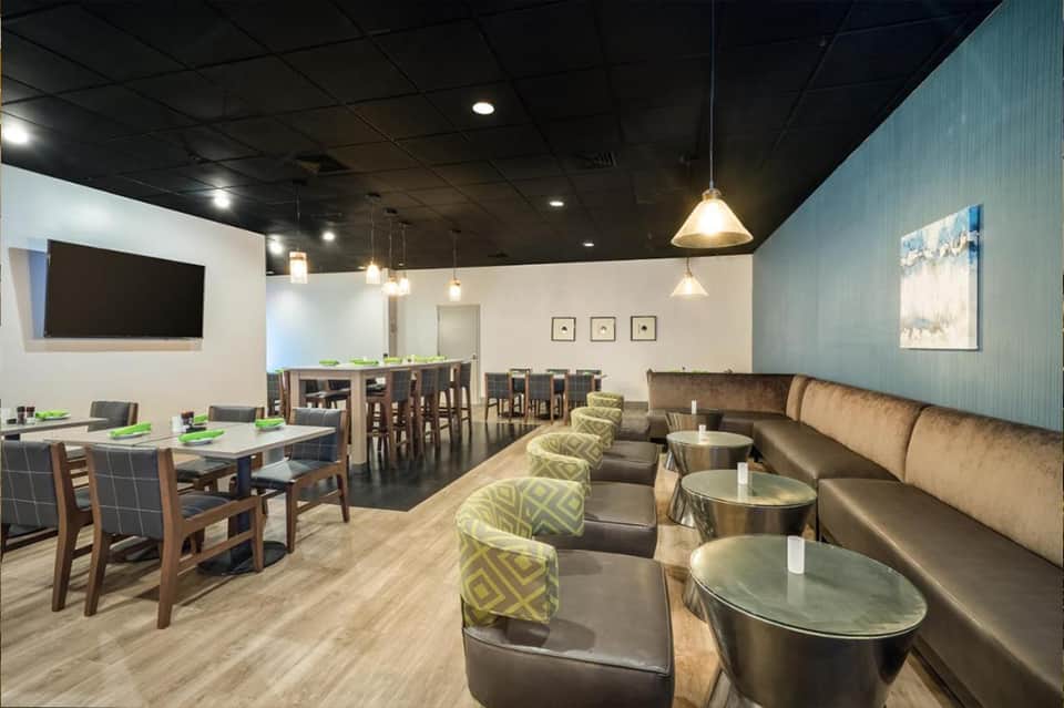 Hotel lounge with dining area, booth seating, pendant lighting, and decorative wall accents