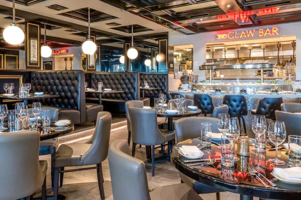Upscale seafood restaurant interior with black tufted banquettes, modern lighting, and Claw Bar signage