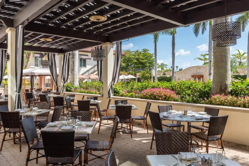 Upscale outdoor dining terrace with pergola, flowers, and city views