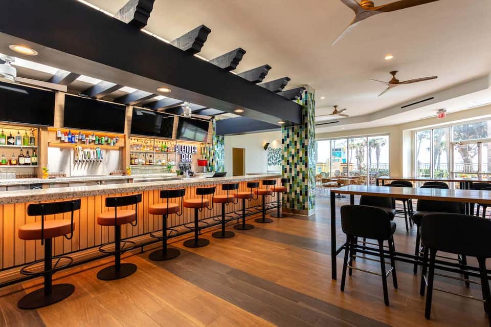 Modern bar with orange stools, wood counters, and coastal decor