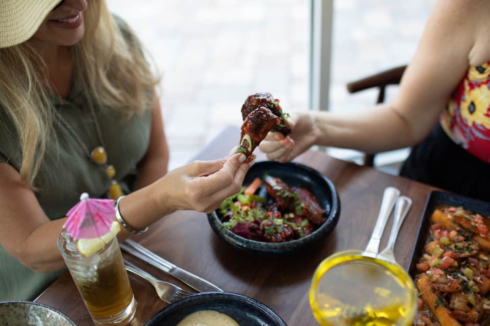 Diners enjoying appetizers and drinks at a restaurant with ocean view window