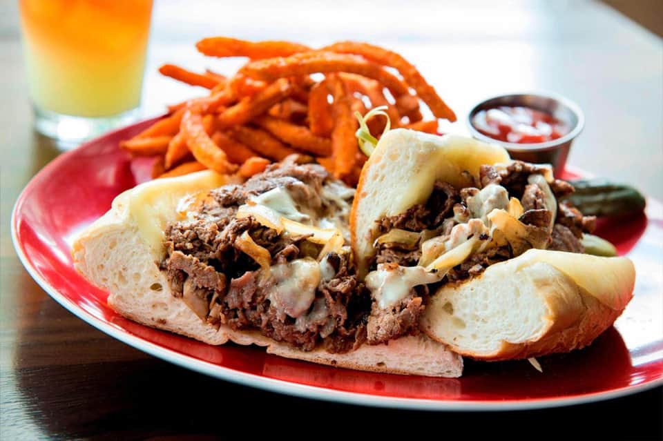 Pulled pork sandwiches with sweet potato fries and beverages on a red plate