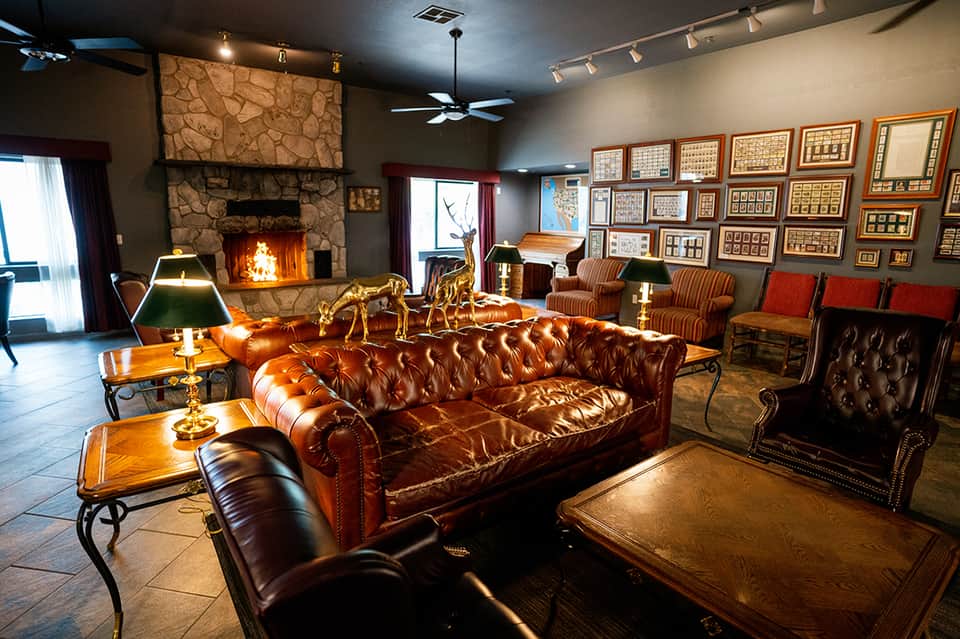 Luxurious lounge with leather chesterfield sofa, fireplace, and framed artwork collection