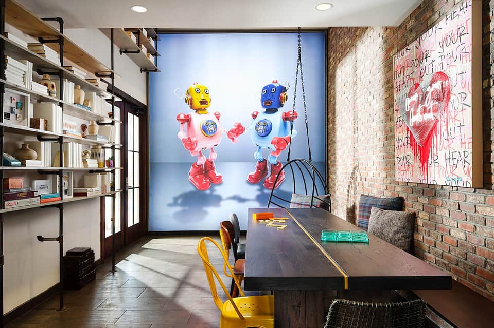 Playroom with colorful robot toys, brick walls, yellow chairs, and art display