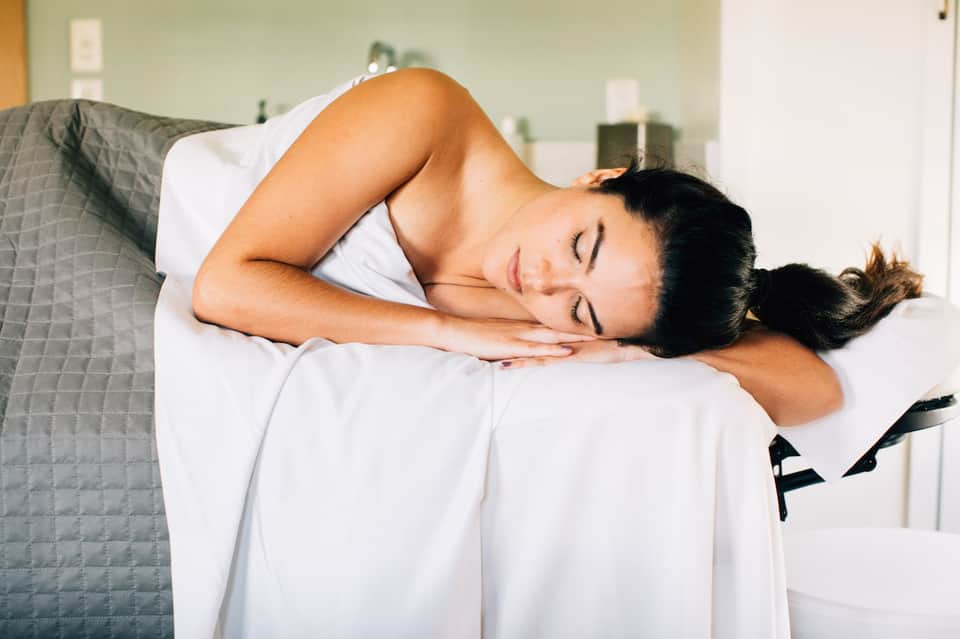Woman sleeping peacefully on white bedding in a bright bedroom with gray accent wall