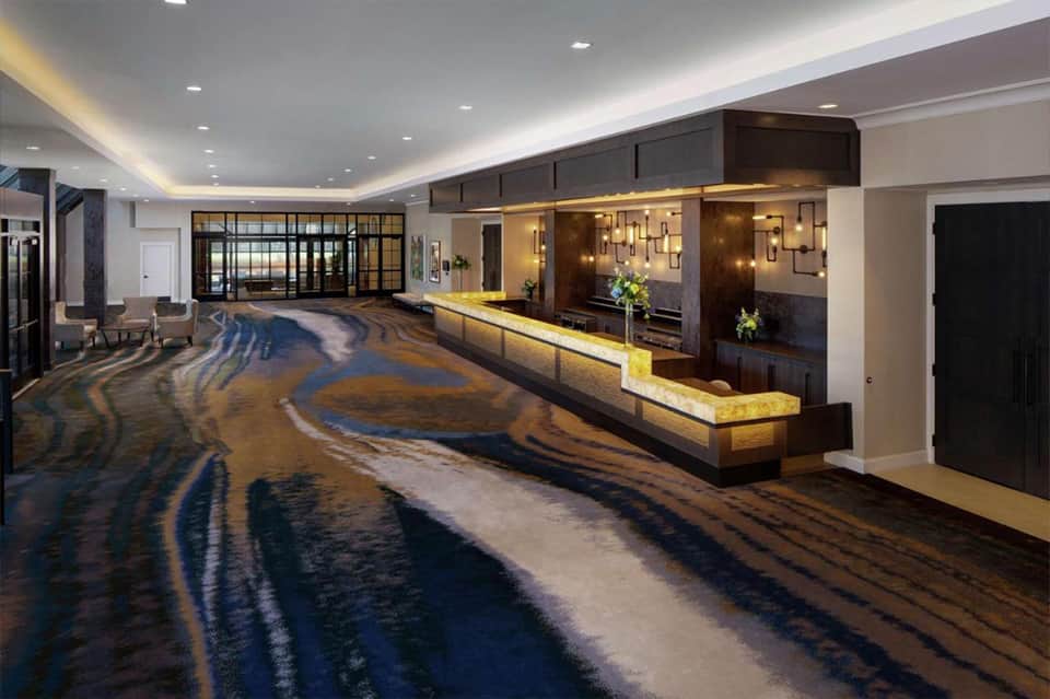 Hotel lobby with polished floors and illuminated reception desk against brown brick wall