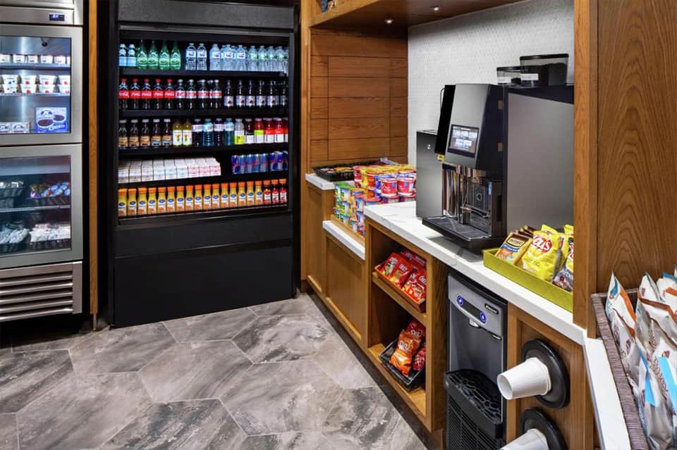 Hotel convenience store interior with refrigerated beverages, snacks, and coffee machine