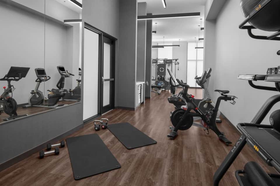 Modern fitness center with exercise bikes, treadmills, dumbbells, and mirrored walls