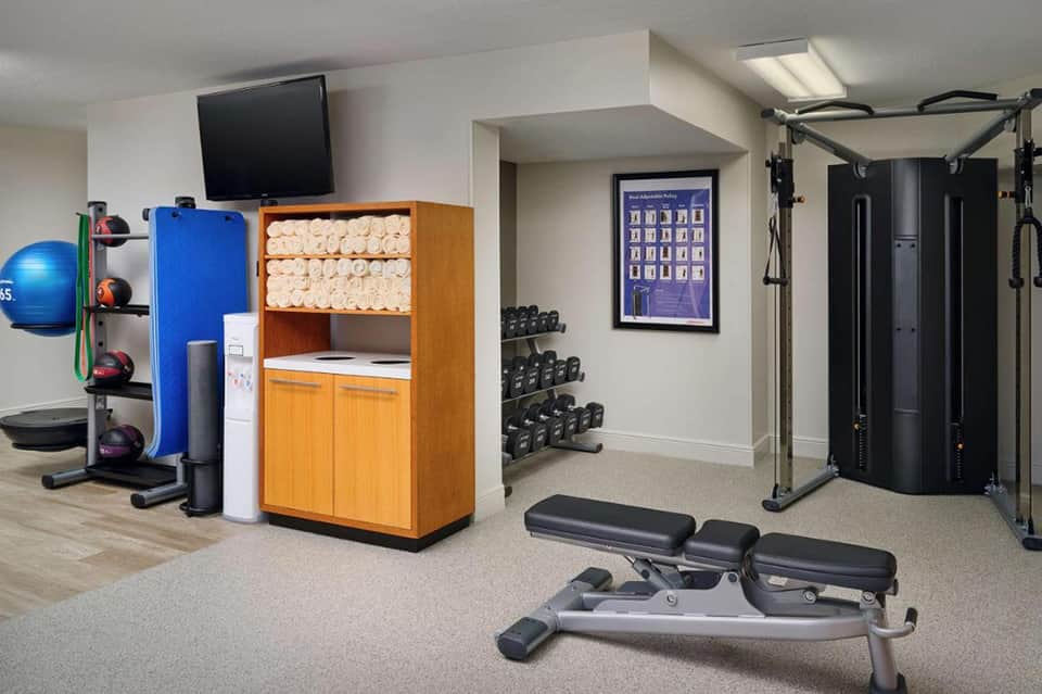 Home fitness center with exercise equipment, dumbbells, medicine balls, and gym machines