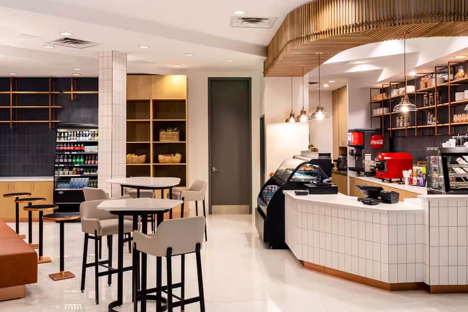 Modern café interior with wooden accents, white tile counter, pendant lights, and seating area