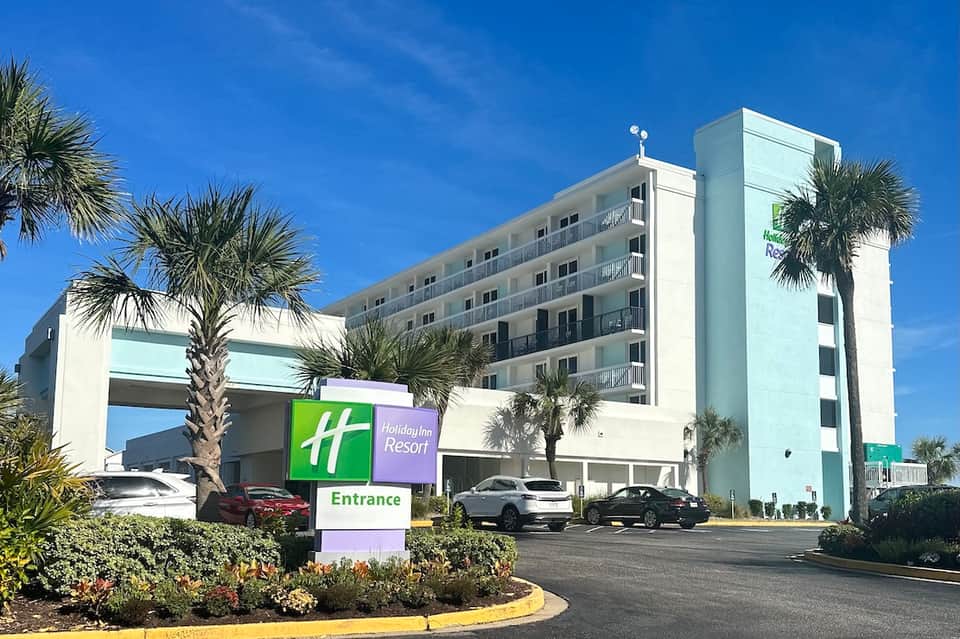 Holiday Inn Resort exterior with palm trees, entrance sign, and beige multi-story building under blue sky