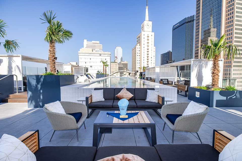 Modern rooftop lounge with city skyline views, palm trees, and contemporary seating