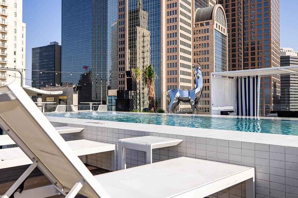 Rooftop infinity pool with downtown skyline views and lounge chairs