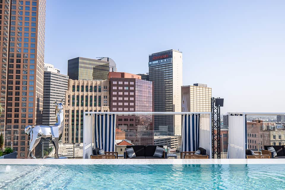 Rooftop pool with city skyline views and blue striped cabana partitions