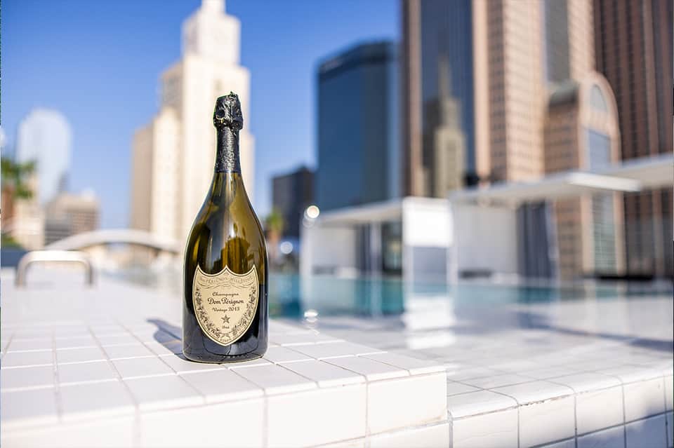 Dom Pérignon champagne bottle on rooftop terrace overlooking downtown city skyline and pool