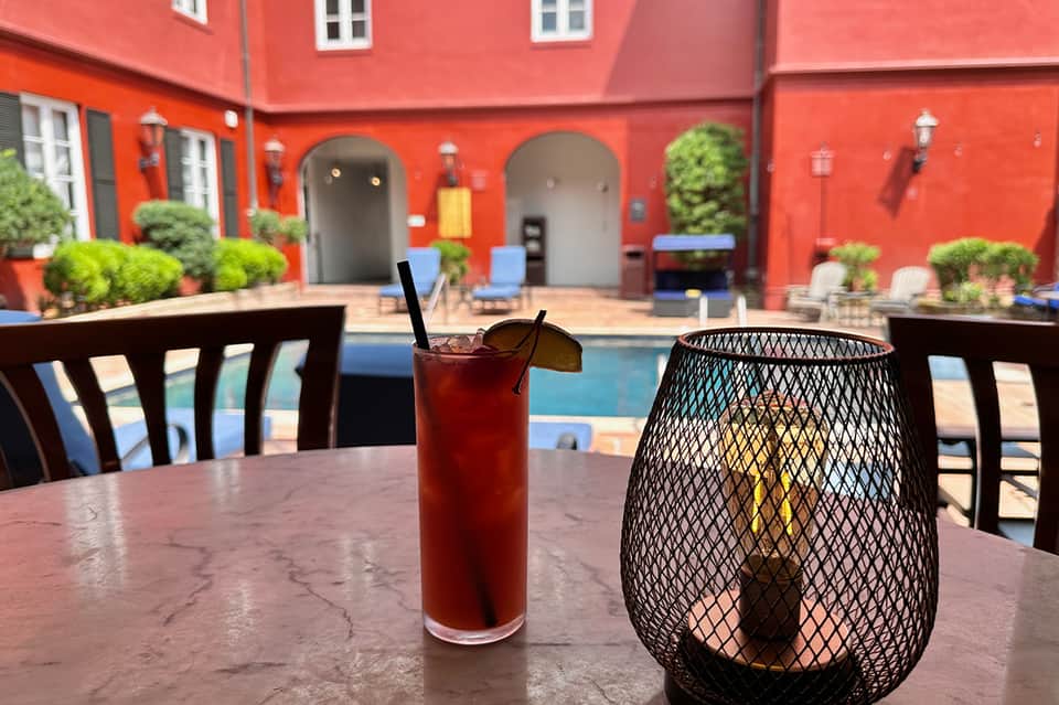 Vibrant red courtyard with poolside seating, cocktail drink, and mesh lantern on marble table