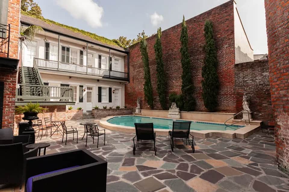 Courtyard pool surrounded by red brick walls, two-story building, ivy-covered roof, and landscaping