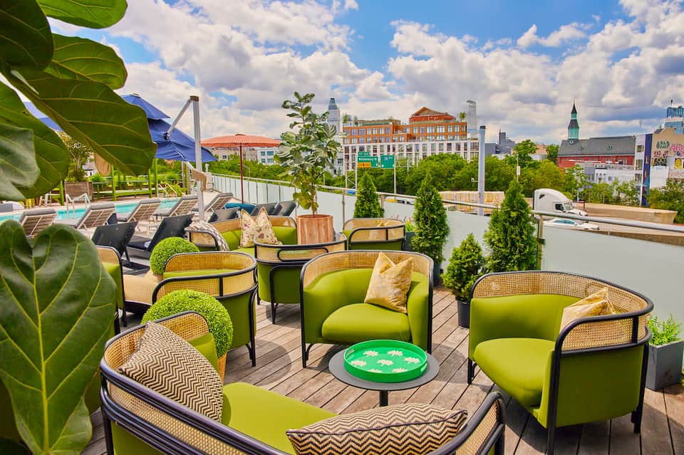 Rooftop lounge with lime green chairs, woven accents, and urban cityscape backdrop