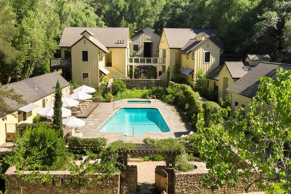 Aerial view of resort compound with yellow cottage-style buildings and central swimming pool