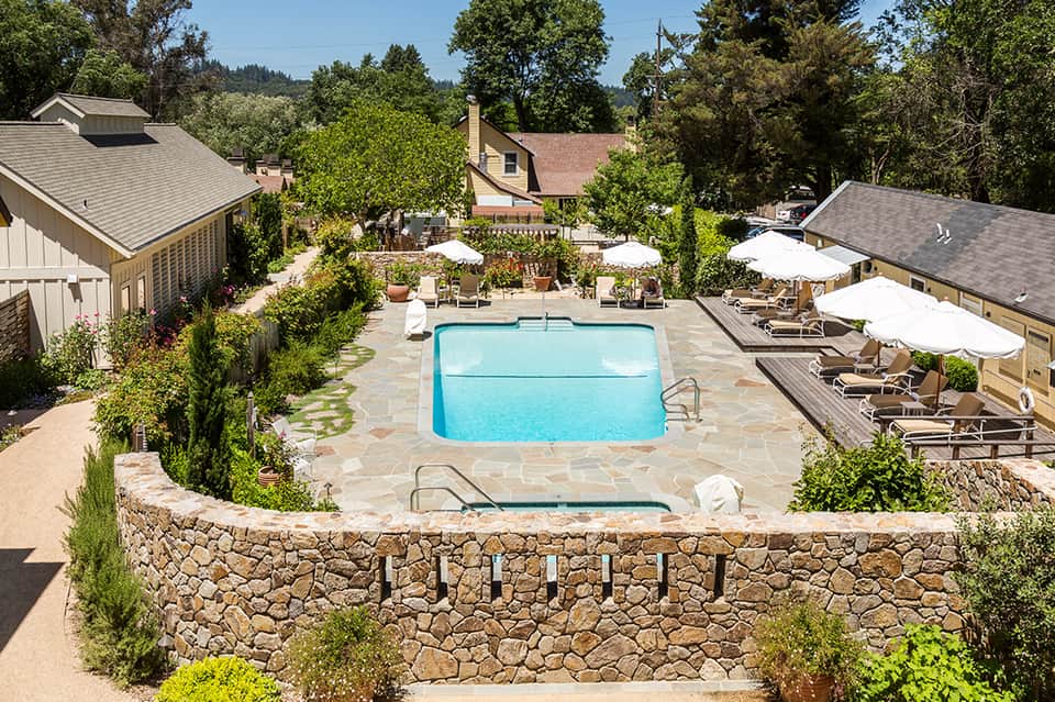 Resort pool surrounded by stone walls, lounge chairs, and umbrella seating areas