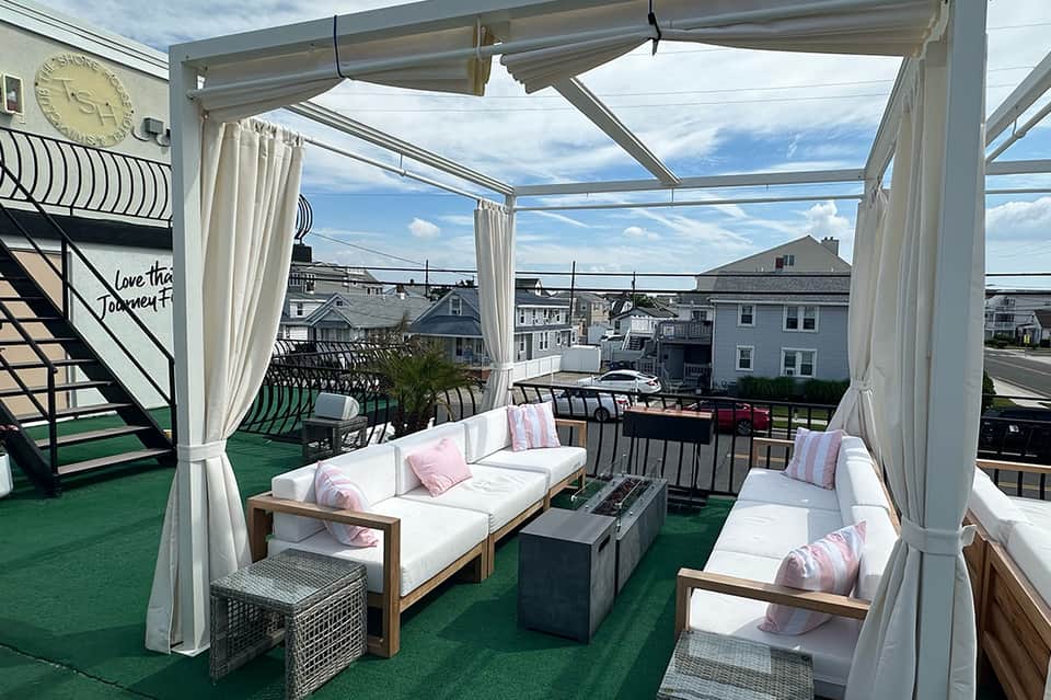 Rooftop lounge with white pergola, comfortable seating, and ocean view
