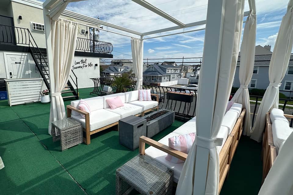 Modern rooftop lounge with white curtained pergolas, seating areas, and coastal views