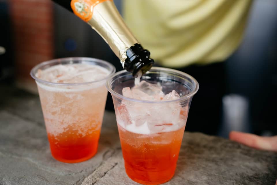 Champagne bottle pouring into two glasses of sparkling cocktail with ice