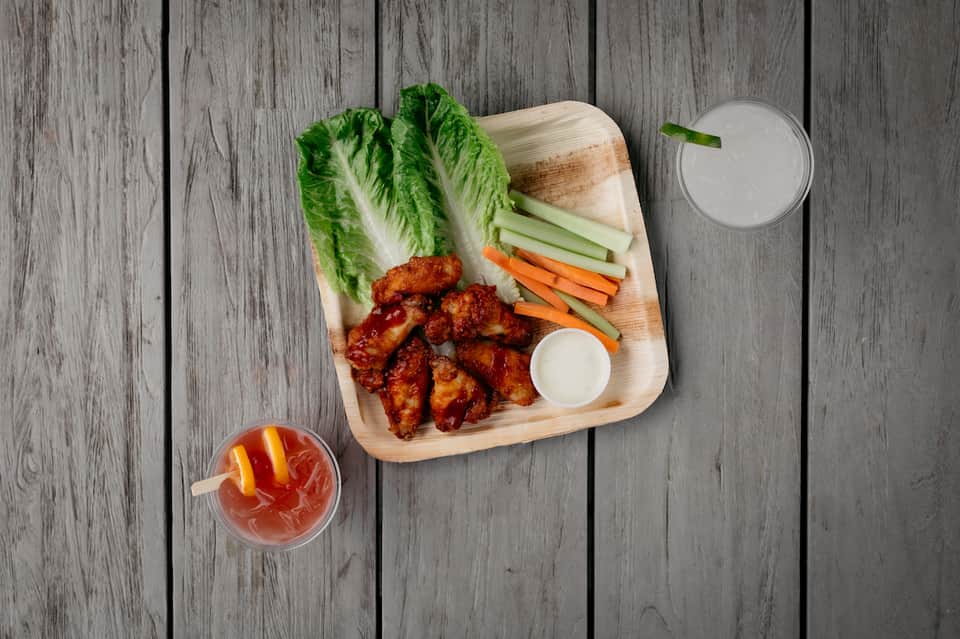 Spicy chicken wings with fresh lettuce, cucumber and carrot sticks, served with white dipping sauce and cocktail