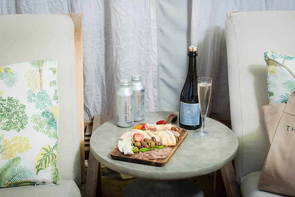 Charcuterie board with meats, cheese, and wine on marble table in cabana