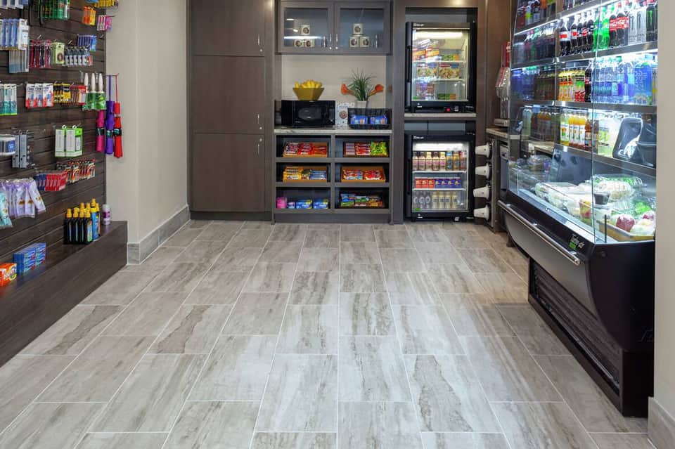 Hotel convenience store with refrigerated cases, shelving units stocked with beverages and snacks