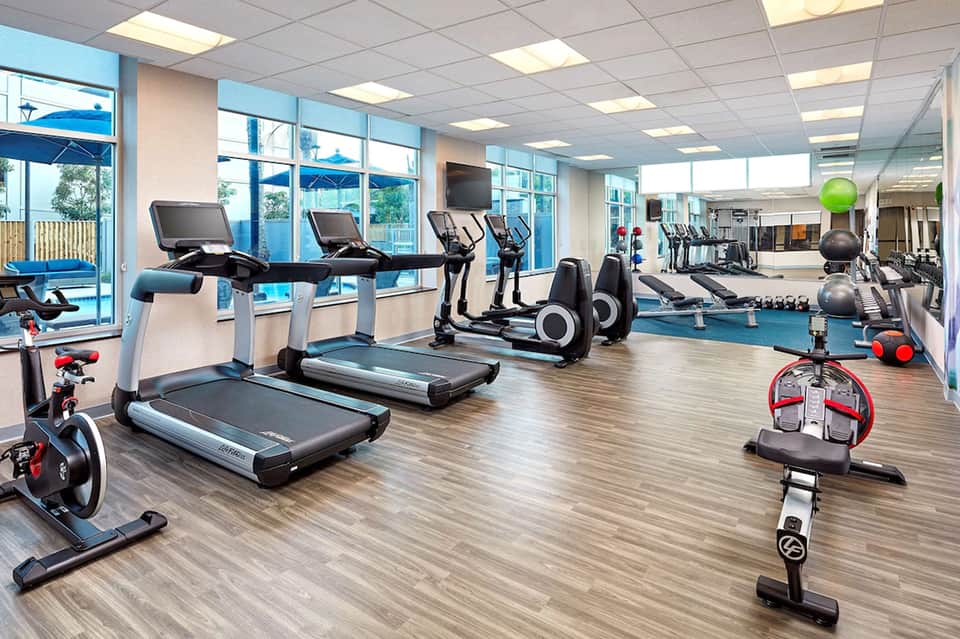 State-of-the-art fitness center with treadmills, exercise bikes, and equipment overlooking outdoor pool